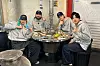 Five Take a Hike! cast members pose around a tabletop grill with food in a casual restaurant.