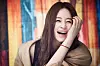 Smiling woman laughing with her hand on her face against a colorful backdrop.