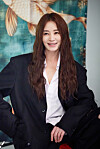 Smiling woman in a black blazer posing before a colorful fish mural.