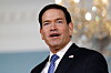 Marco Rubio speaks in a dark suit with an American flag pin at the U.S. State Department.