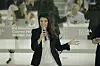 Woman in black blazer speaking into a microphone at a panel event.