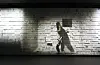 A silhouetted person walks across a lit wall with rectangular geometric patterns.