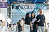 People walk through an indoor venue beneath a large Kia Seoul banner.