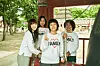 Five people in matching family shirts pose outdoors under a shaded structure.
