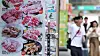 Menu board with Korean dishes outside a Myeongdong restaurant, with pedestrians blurred in the background.