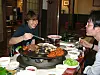 Two diners cook and eat grilled pork at a restaurant table in Daegu.