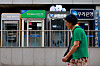 A person walks in front of booths of private banks' automatic teller machines in Seoul on Aug. 17.