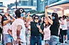 People wearing headphones dance and cheer together in an outdoor urban setting.
