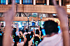 Crowd members hold up phones outside a brightly lit venue at night.