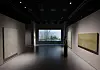 A staff member stands among minimalist artworks in a dimly lit museum gallery.