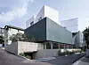 Contemporary angular building with dark walls and white geometric upper sections on an urban street.