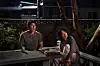 Ho-seok and Mi-ok sit at a picnic table with food and drinks beneath trees at night.