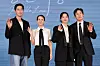 Four actors in formal attire wave in front of a blue backdrop at a film press event.