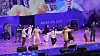 A group of performers acts on a purple-lit stage during a Gag Concert parody of KBS.