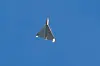 A Shahed drone flies against a clear blue sky over Kyiv.