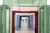 A corridor with layered green, red and blue door frames and visitors visible in the distance.