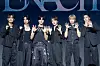 Six performers in black outfits pose together beneath an ENHYPEN backdrop.