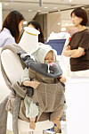 Baby carrier display with a mannequin and knitted accessories in a department store.