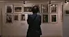 Visitor viewing framed artworks displayed on a gallery wall.