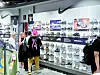 Shoppers browse Nike sneakers and apparel in a brightly lit retail store.