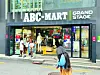 People outside an ABC-MART Grand Stage shoe store with merchandise visible inside.