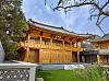 Traditional Korean wooden pavilion with ornate details in a landscaped courtyard.