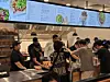 Crowded restaurant counter with customers ordering beneath illuminated menu boards.