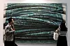 Two visitors examine a large textured abstract artwork in a gallery at Frieze Seoul.