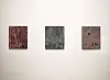 Three textured abstract artworks hang side by side on a white wall.