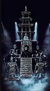 Masked performers gather around a central figure on a smoky, blue-lit gothic stage.