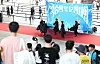 Costumed performers dance onstage while spectators watch at a Seoul museum event.