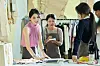 Han So-hee as Seon-woo stands at a worktable with colleagues in a clothing studio.