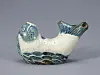 White and blue glazed ceramic fish sculpture on a gray surface.