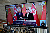 A TV screen shows an image of Chinese President Xi Jinping, left, and North Korean leader Kim Jong-un, during a news program at a bus terminal in Seoul, on June 9.