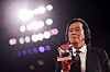 Lee Chang-dong holds a Silver Lion trophy beneath bright stage lights.