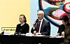 Three panelists sit at a table as the central speaker addresses the audience at a Hyundai event.