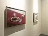 Gallery wall with a red still-life painting and a smaller framed artwork.