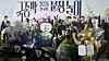 A large group in colorful costumes poses beneath a Korean event banner at a Seoul museum.