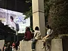 People gather beside a large wall mural in an urban outdoor setting.