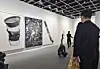 Visitors walk through the Johyun Gallery booth, viewing three contemporary artworks on a white gallery wall.