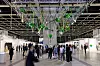 Visitors view a suspended green installation beneath the exhibition hall ceiling at Art Basel Hong Kong 2023.