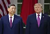 Donald Trump and Xi Jinping stand side by side before U.S. and Chinese flags.