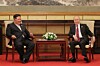 Kim Jong Un and Vladimir Putin sit in armchairs beside a flower arrangement in a formal room.
