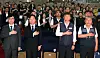 Four officials stand with hands over their hearts before an audience during a Seoul labor committee ceremony.