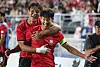 Two South Korean players in red celebrate together during a soccer friendly against Ecuador.