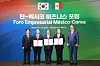 Five delegates pose onstage beneath a Korea-Mexico business forum banner and two national flags.