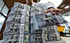 A person holds a bundle of dollars at a Hana Bank in central Seoul on Sept. 3.