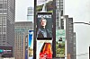 A Times Square billboard shows a portrait of Jensen Huang in a leather jacket beneath the word “Architect.”