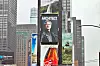 A Times Square billboard shows a portrait of Jensen Huang in a leather jacket beneath the word “Architect.”