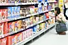 Shopper crouches beside shelves of colorful packaged snacks in a Korean supermarket.